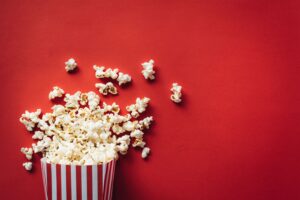 Striped bucket of popcorn spilling onto red background